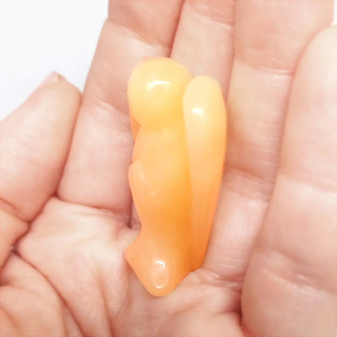 Carved Orange Calcite Angel figurine with smooth polished finish and glowing orange tones.