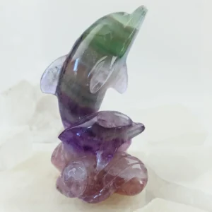 Rainbow fluorite dolphin pair carving with visible natural color bands.