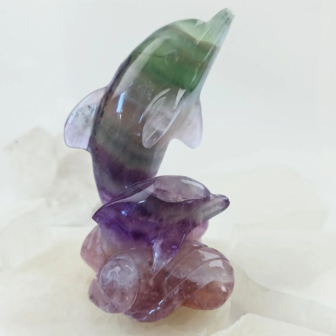 Rainbow fluorite dolphin pair carving with visible natural color bands.