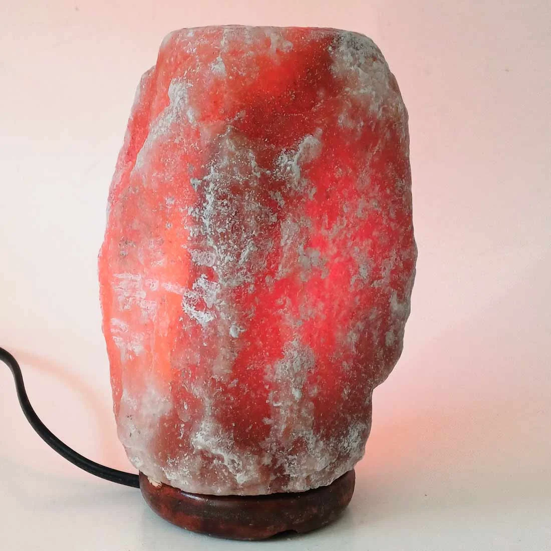 maroon Himalayan salt lamp on wooden base