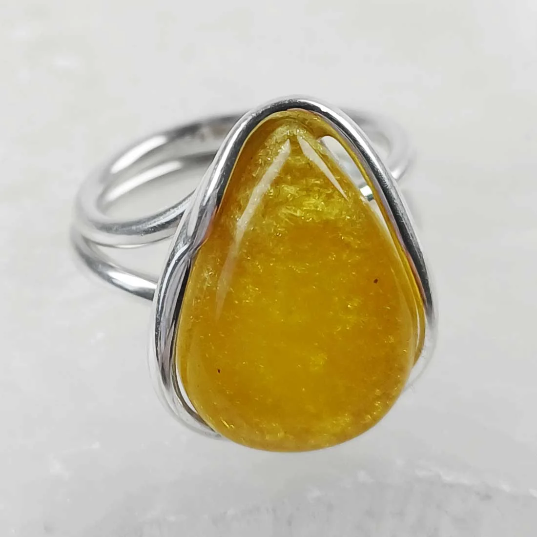 Yellow-toned natural amber ring set in 925 sterling silver, showing warm honey color and smooth polished surface.