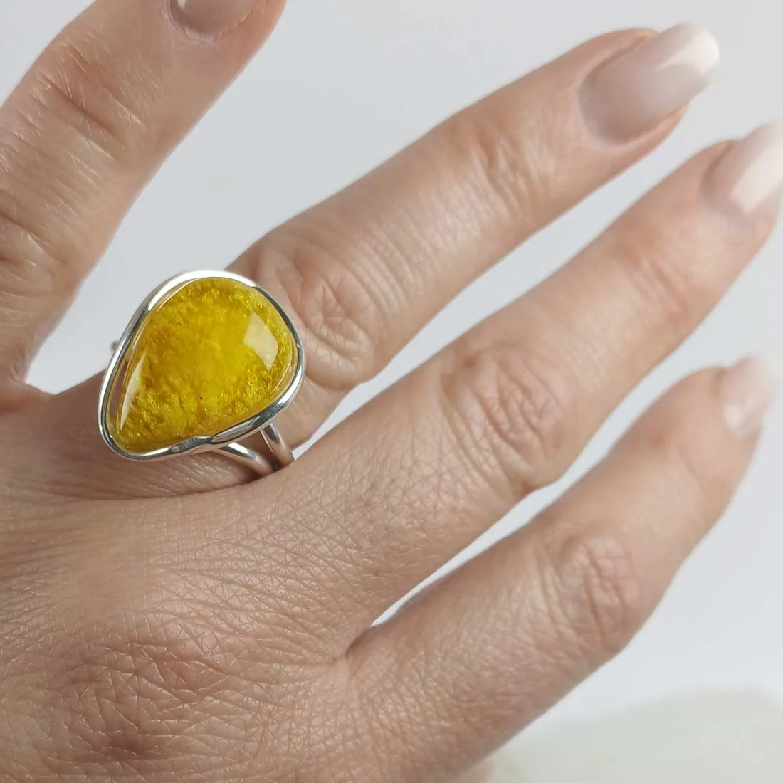 Yellow-toned natural amber ring set in 925 sterling silver, showing warm honey color and smooth polished surface.