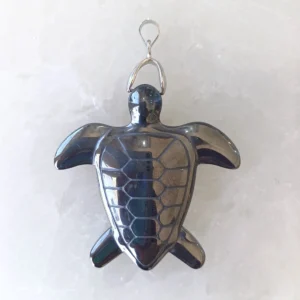Carved hematite turtle pendant with polished metallic surface and metal hook.