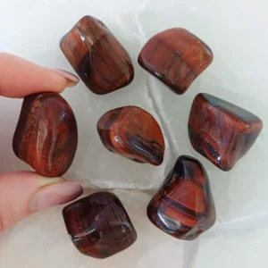 Polished Red Tiger Eye tumbled stone with deep reddish brown tones and silky chatoyant bands, crystal associated with motivation and confidence