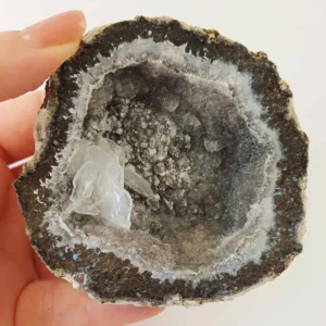 Natural agate geode from Mexico with banded exterior and druzy crystal interior in grey and translucent tones.