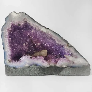 Small amethyst cave with purple crystal points and natural agate edge on a flat base